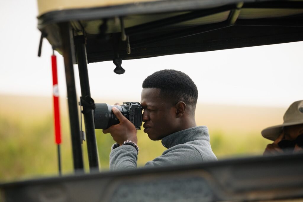 Filbert Minja, founder of Reearth Gallery, capturing photographs during a climate-focused multimedia exhibition.